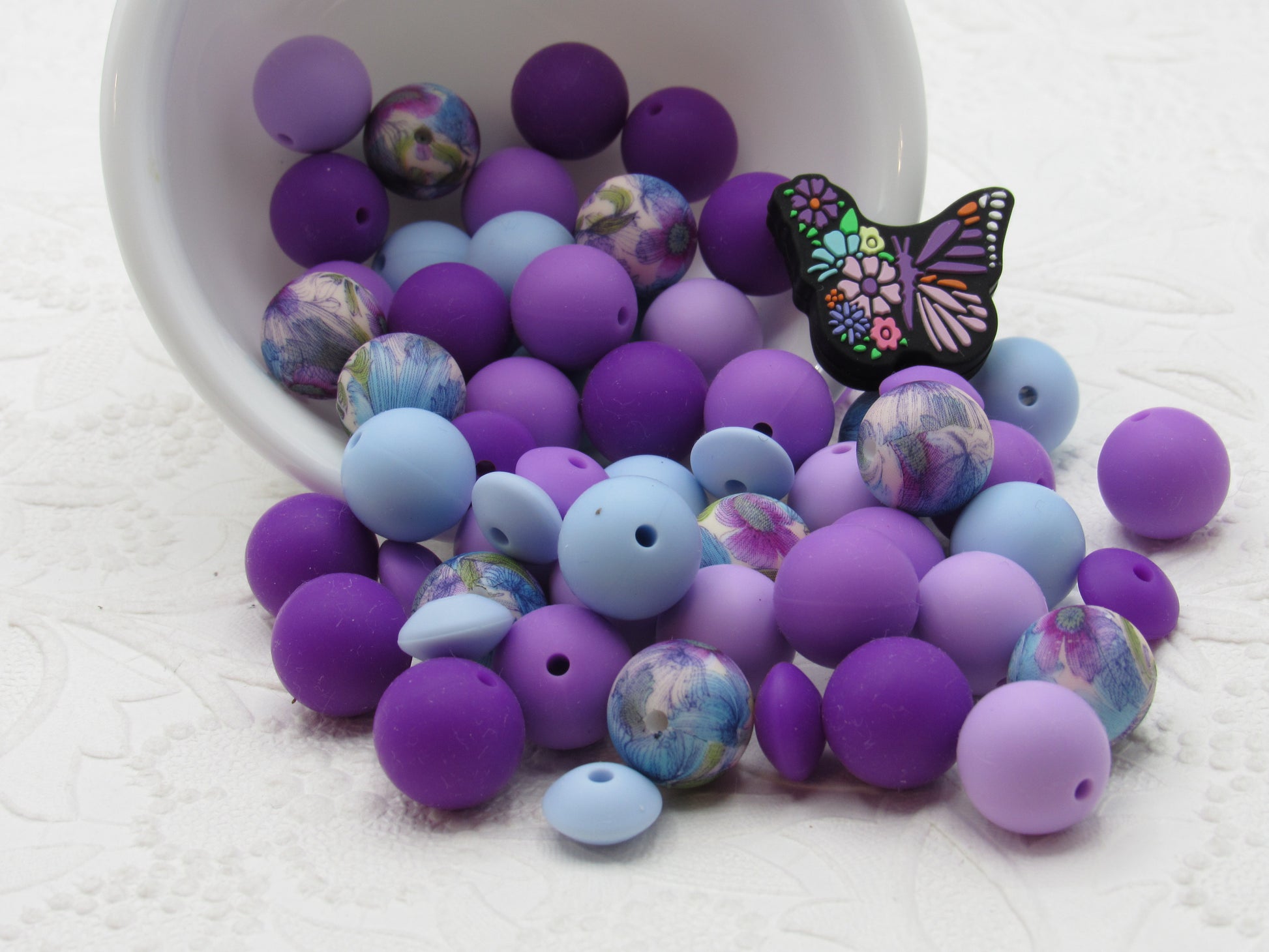 Purple and blue silicone beads with a butterfly Silicone Bead on a black surface